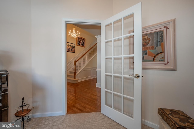 hallway featuring a notable chandelier and carpet floors