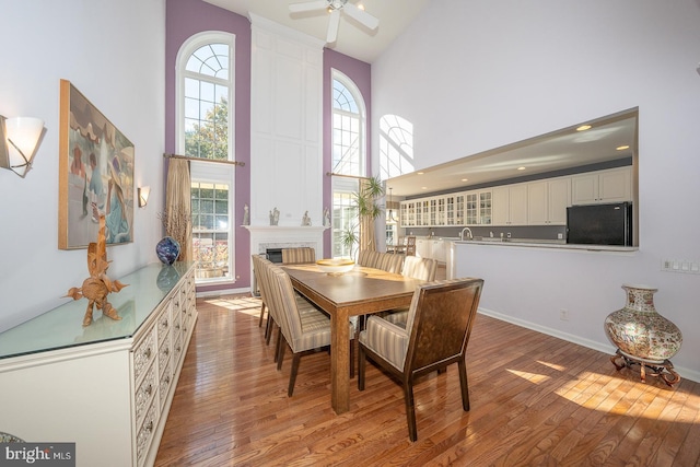 dining area featuring a towering ceiling, hardwood / wood-style flooring, and a healthy amount of sunlight