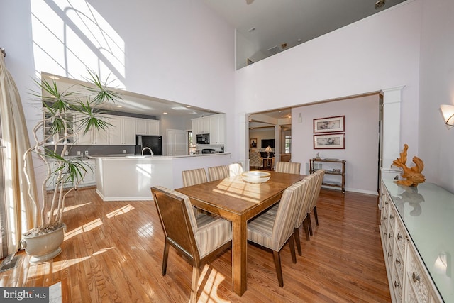 dining area featuring a high ceiling and light hardwood / wood-style flooring