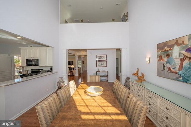 dining area featuring a high ceiling and dark wood-type flooring