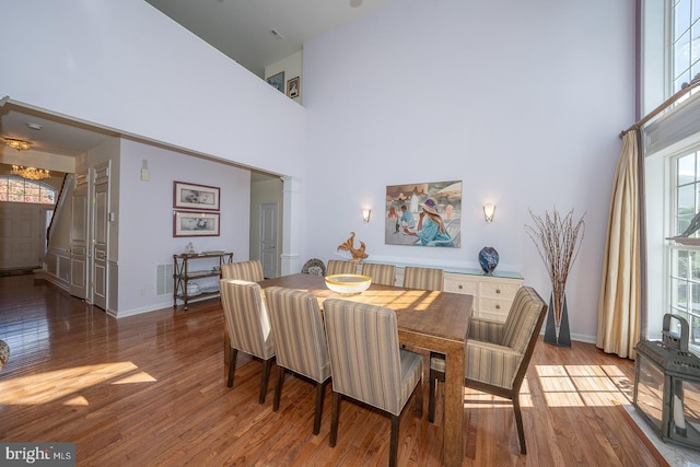 dining space with hardwood / wood-style floors and a towering ceiling