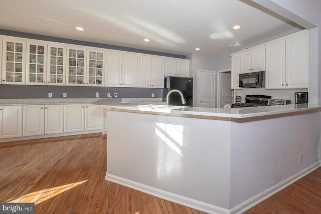 kitchen featuring black appliances, light hardwood / wood-style floors, white cabinetry, and kitchen peninsula