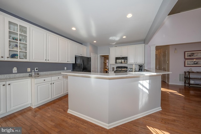 kitchen with an island with sink, white cabinets, black appliances, and light hardwood / wood-style floors