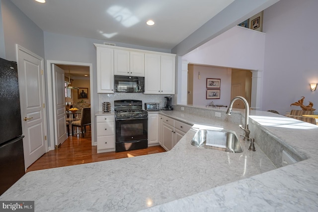 kitchen featuring tasteful backsplash, light stone counters, sink, black appliances, and white cabinets