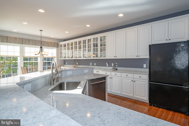 kitchen featuring white cabinetry, dishwasher, sink, light stone counters, and black refrigerator