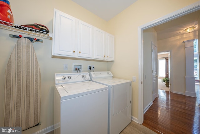 clothes washing area with cabinets, hardwood / wood-style floors, and washer and clothes dryer