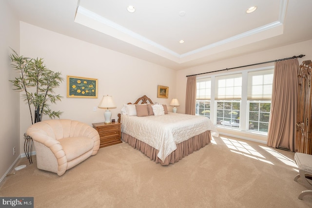 bedroom featuring a raised ceiling, crown molding, and light colored carpet