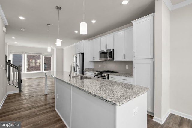 kitchen featuring a kitchen island with sink, sink, white cabinets, pendant lighting, and appliances with stainless steel finishes