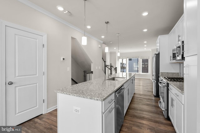 kitchen with appliances with stainless steel finishes, white cabinetry, hanging light fixtures, and a center island with sink