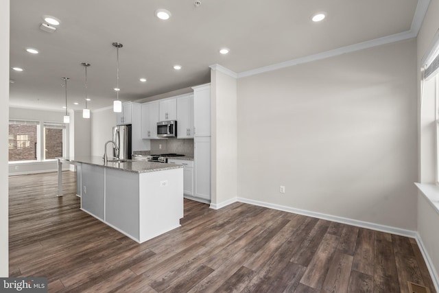 kitchen featuring dark wood-type flooring, a center island with sink, decorative light fixtures, white cabinetry, and appliances with stainless steel finishes