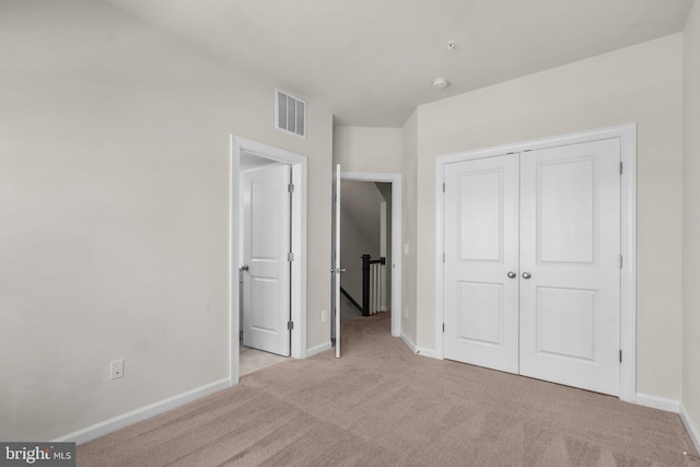 unfurnished bedroom featuring light carpet and a closet