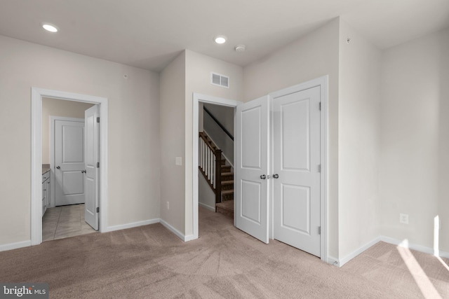 unfurnished bedroom with light carpet and ensuite bath