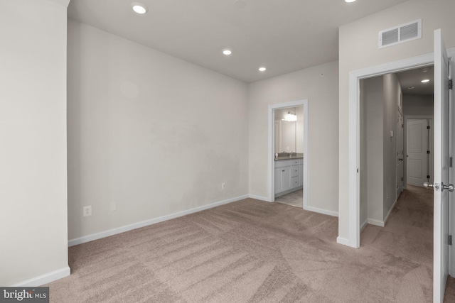 unfurnished bedroom with connected bathroom and light colored carpet