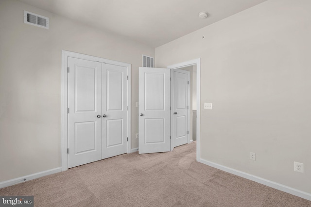 unfurnished bedroom featuring light carpet and a closet