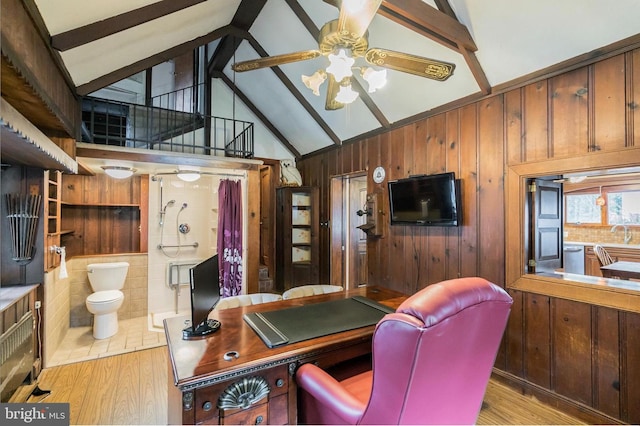 office area with beam ceiling, light wood-type flooring, wooden walls, and ceiling fan