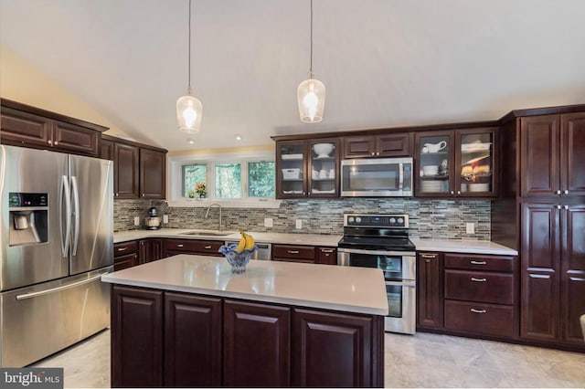 kitchen featuring appliances with stainless steel finishes, sink, a kitchen island, lofted ceiling, and decorative light fixtures