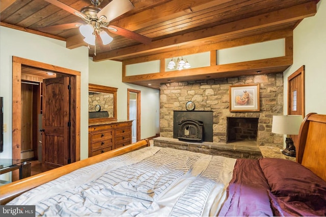 bedroom featuring wood ceiling, a wood stove, beam ceiling, and ceiling fan