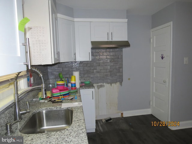 kitchen featuring decorative backsplash, white cabinets, dark wood-type flooring, sink, and light stone counters