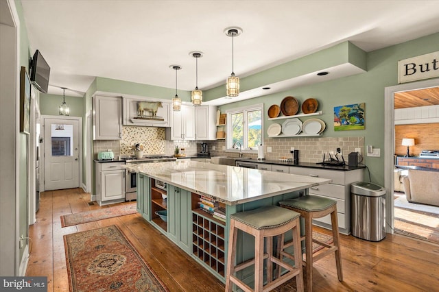 kitchen with stainless steel stove, light wood-type flooring, decorative backsplash, and a kitchen island