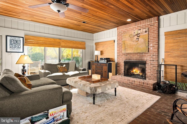 living room featuring wooden ceiling, ceiling fan, and a brick fireplace