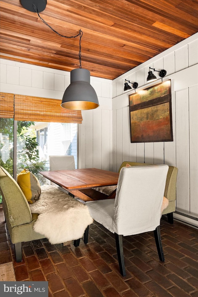 dining space with wooden ceiling, breakfast area, and wooden walls