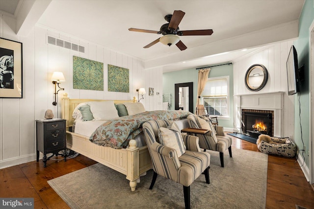 bedroom featuring ceiling fan, dark hardwood / wood-style floors, a fireplace, and ornamental molding