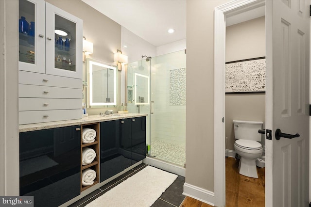 bathroom with hardwood / wood-style flooring, vanity, toilet, and walk in shower