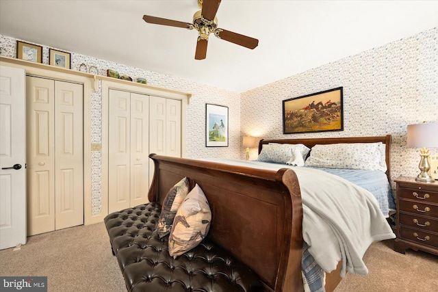 carpeted bedroom featuring ceiling fan and two closets