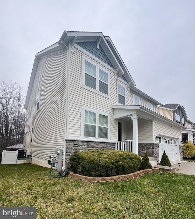 view of front of house featuring a garage, a porch, a front yard, and central AC