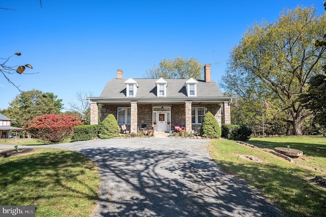 cape cod home featuring a porch and a front lawn