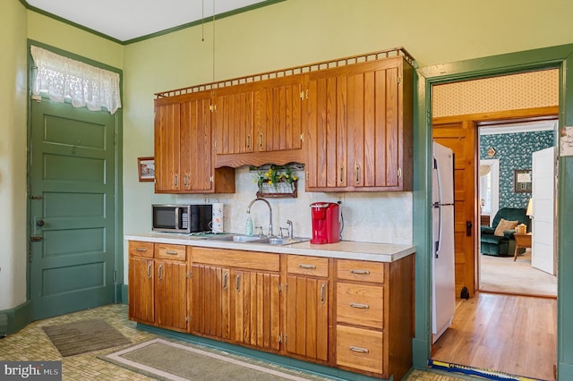 kitchen with crown molding, light hardwood / wood-style floors, sink, and white fridge