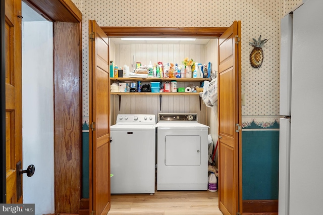 clothes washing area with light hardwood / wood-style flooring and washer and dryer