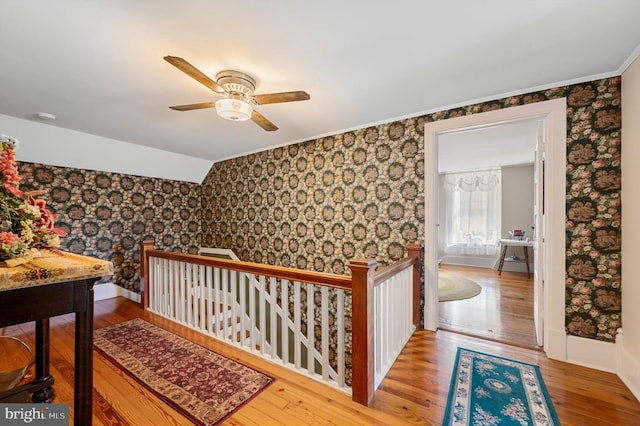 hall with hardwood / wood-style flooring, ornamental molding, and lofted ceiling