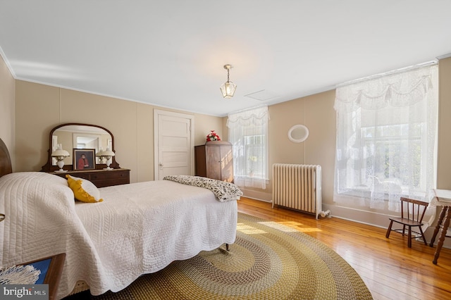 bedroom featuring multiple windows, radiator heating unit, and light hardwood / wood-style floors