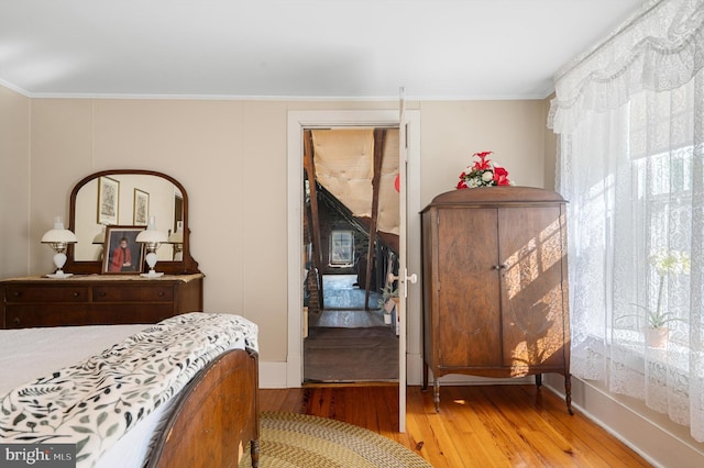 bedroom featuring multiple windows, wood-type flooring, and crown molding