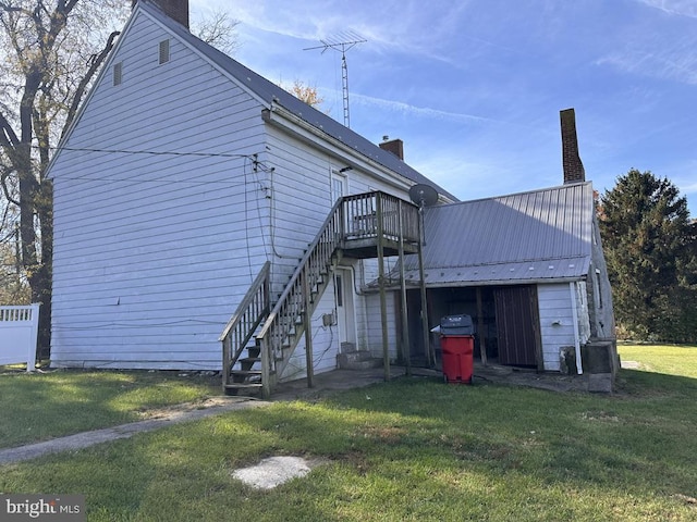 rear view of property with a wooden deck and a lawn