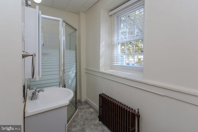 bathroom featuring vanity, radiator heating unit, wooden walls, and an enclosed shower