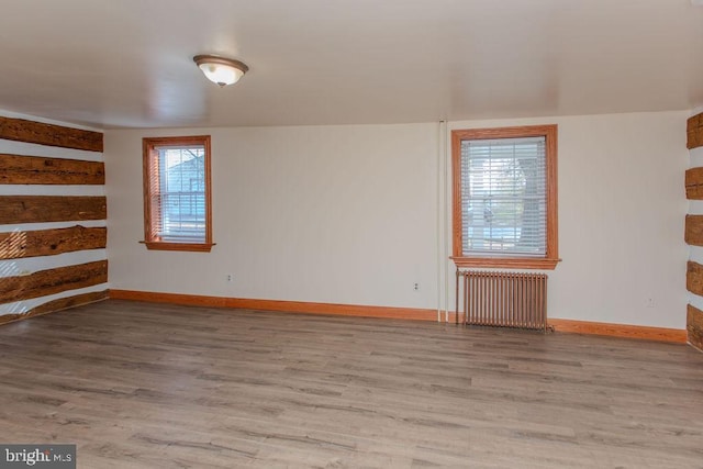 unfurnished room with a healthy amount of sunlight, radiator heating unit, and light wood-type flooring