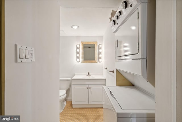 bathroom with toilet, vanity, tile patterned flooring, and stacked washer / drying machine