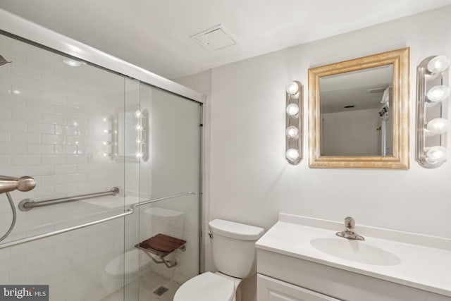 bathroom with a shower with door, vanity, and toilet