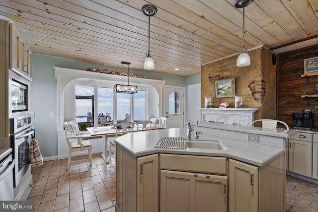 kitchen featuring a kitchen island with sink, appliances with stainless steel finishes, wood walls, and sink