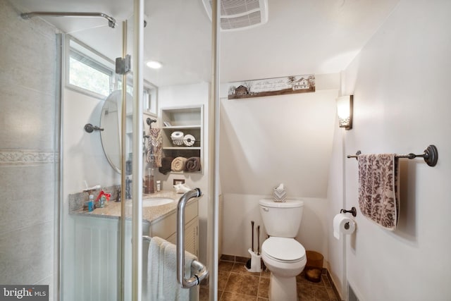 bathroom featuring tile patterned flooring, vanity, toilet, and a shower with door