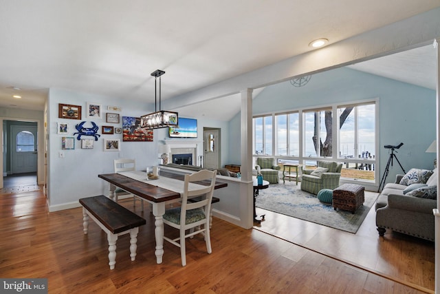 dining room with hardwood / wood-style floors, vaulted ceiling with beams, and an inviting chandelier