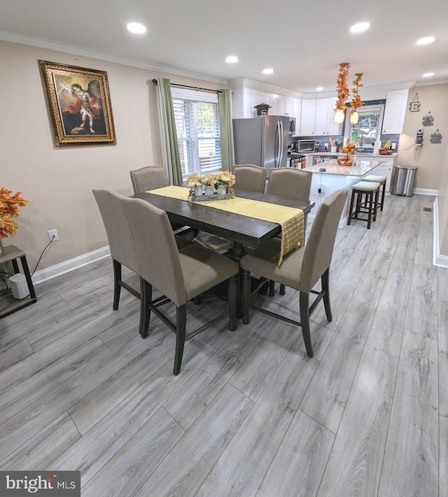 dining area featuring ornamental molding and light wood-type flooring