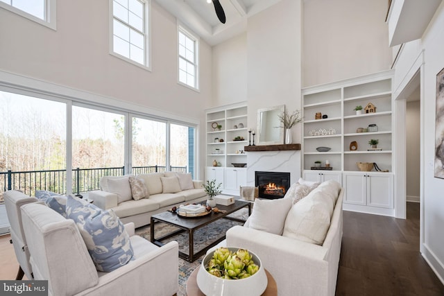 living room with dark hardwood / wood-style flooring, ceiling fan, a healthy amount of sunlight, and a high ceiling