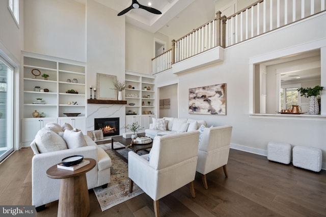 living room with dark wood-type flooring, ceiling fan, and a towering ceiling