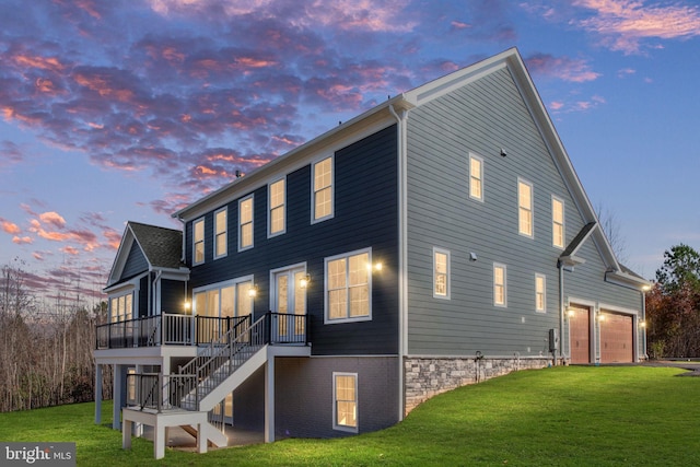 back house at dusk with a deck, a garage, and a yard