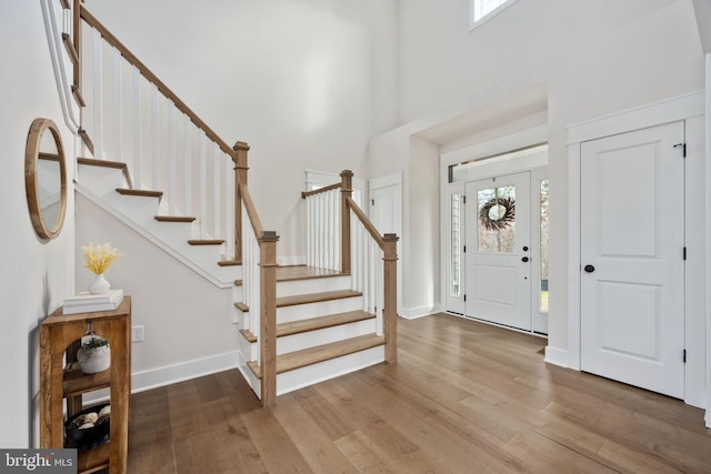 foyer entrance featuring a towering ceiling and hardwood / wood-style flooring