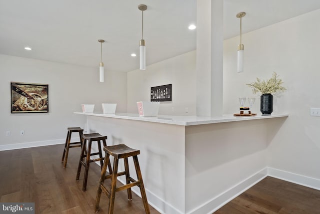 kitchen with hanging light fixtures, a kitchen breakfast bar, dark wood-type flooring, and kitchen peninsula