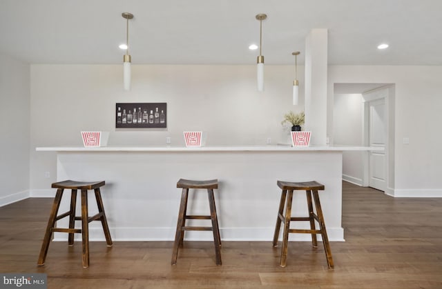 kitchen featuring dark wood-type flooring, a breakfast bar, decorative light fixtures, and kitchen peninsula